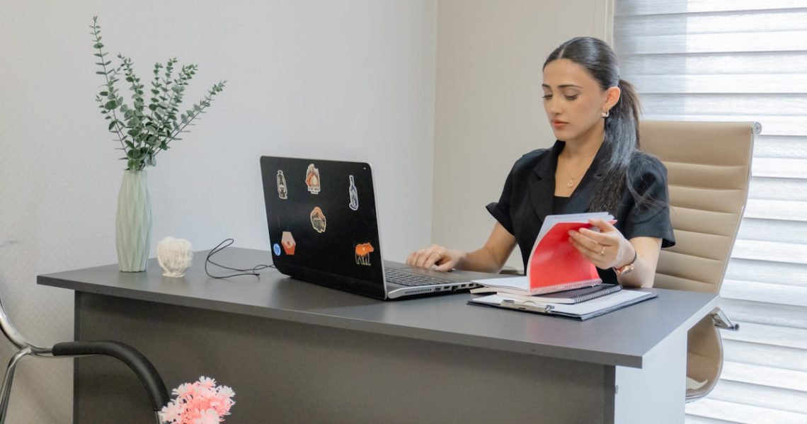 Woman working on a laptop at a desk.