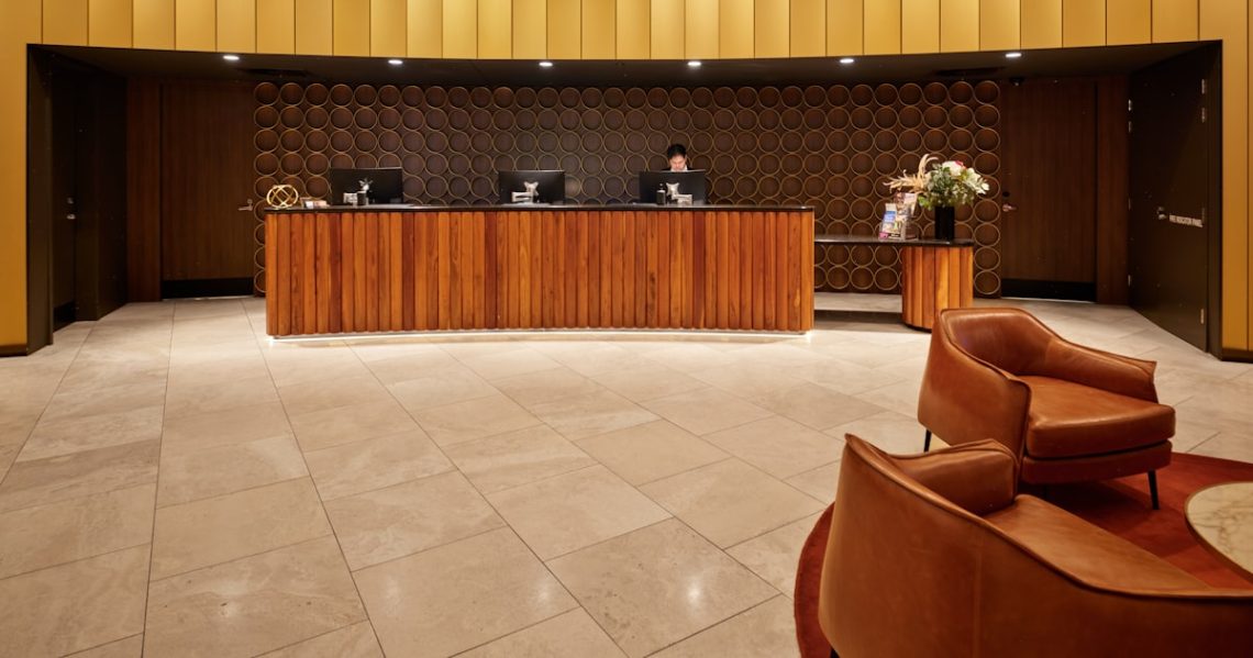 Hotel reception desk with modern wooden furniture and seating.