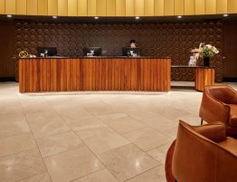 Hotel reception desk with modern wooden furniture and seating.
