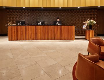 Hotel reception desk with modern wooden furniture and seating.